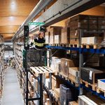 Varastotyöntekijä kerää tavaraa logistiikkakeskuksen hyllyvälissä.